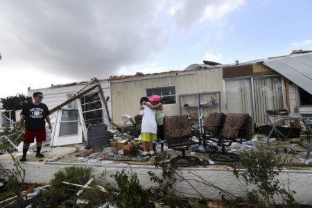 Olga Teakell hugs her grandson Gabriel Melendez, 9, after he cut his finger on glass, while he and his bother Ellisha Melendez, 12, left, help clean debris from Olga's destroyed home, in the Naples Estates mobile home park, in the aftermath of Hurricane Irma in Naples, Fla., Monday, Sept. 11, 2017. (AP Photo/Gerald Herbert)