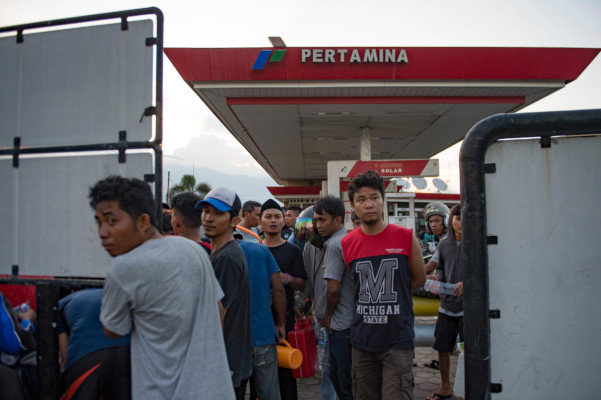 People siphon gasoline from a petrol station in Palu in Central Sulawesi on September 29, 2018, after a strong earthquake and tsunami struck the area. / AFP PHOTO / Bay ISMOYO People siphon gasoline from a petrol station