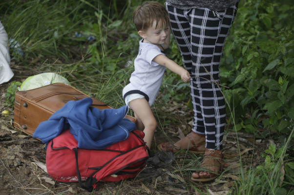 A young Honduran migrant stands with a woman as they travel with a caravan of migrants moving toward the country's border with Guatemala, in Ocotepeque, Honduras, Monday, Oct. 15, 2018. (AP Photo/Moises Castillo) young Honduran migrant stands with a woman