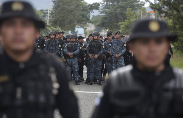 Guatemalan police stand in the road to block Honduran migrants making their way to the U.S., in Esquipulas, Guatemala, Monday, Oct. 15, 2018. (AP Photo/Moises Castillo) Guatemalan police stand in the road to block Honduran migrants
