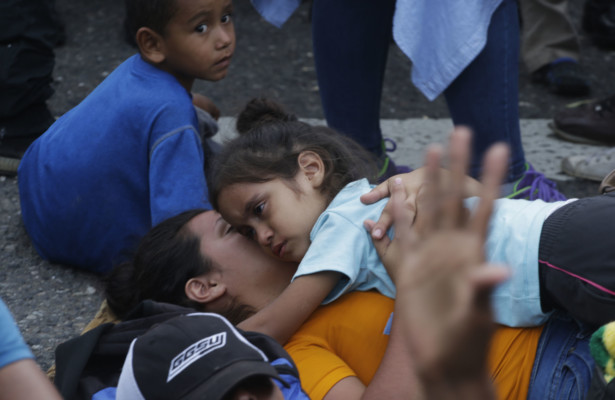 A Honduran migrant mother and child rest where Guatemalan police block the road after their caravan crossed the Honduras-Guatemala border without incident, in Esquipulas, Guatemala, Monday, Oct. 15, 2018. Castillo) Honduran migrant mother and child rest