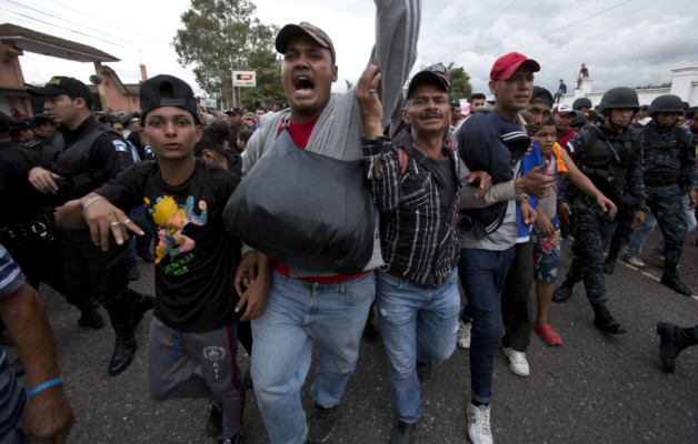 Honduran migrants walk past a roadblock of Guatemalan police as they make their way to the U.S., in Esquipulas, Guatemala, Monday, Oct. 15, 2018. Police stopped the migrants for several hours but the travelers refused to return to the border and were eventually allowed to pass. (AP Photo/Moises Castillo) Honduran migrants walk past a roadblock of Guatemalan police