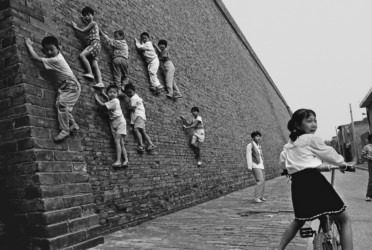 A photo in Xian in 1996 shows a group of kids trying to climb up the ancient wall. (Source: Hu Gongyong’s :“The stories of Sifang City” via VCG)