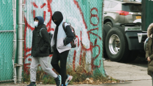 A couple of students are walking on the sidewalk in a derelict part of town.