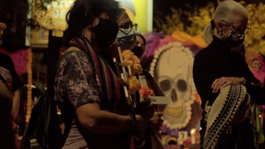 Mourners at a vigil. You can see imagery of death on background.