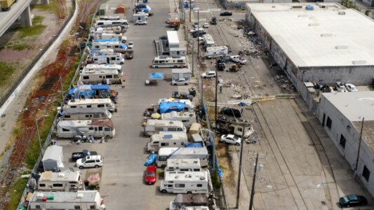 An urban encampment of mainly motor homes alongside a highway in the Bay Area.