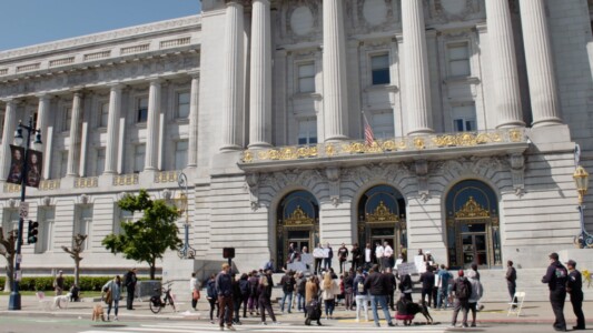 A gathering of people with signs in front of San Francisco's City Hall.